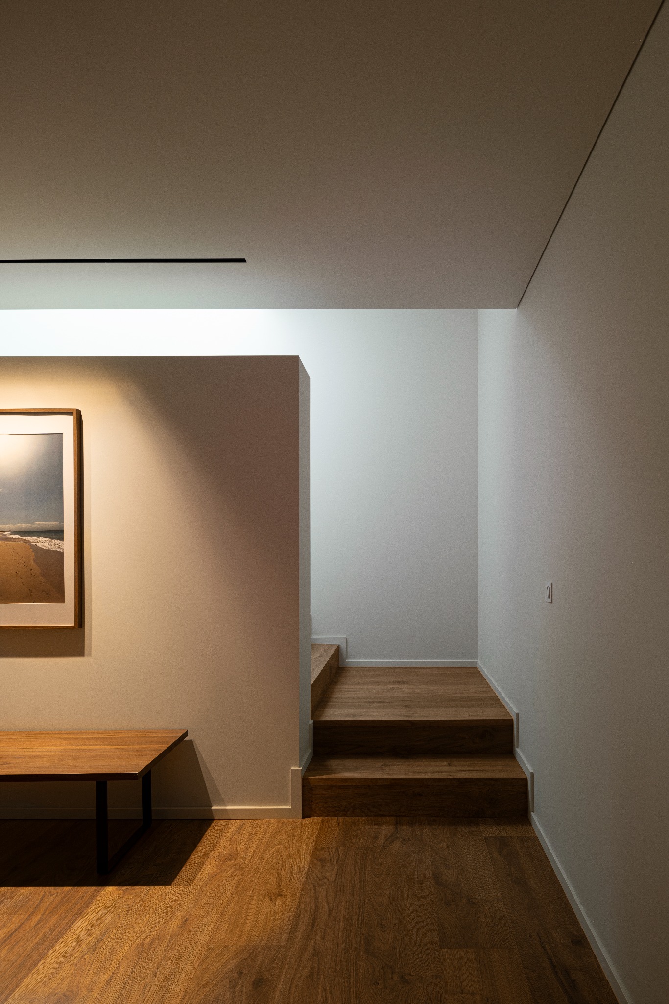 Casa A, escada interior em madeira iluminada por uma abertura zenital